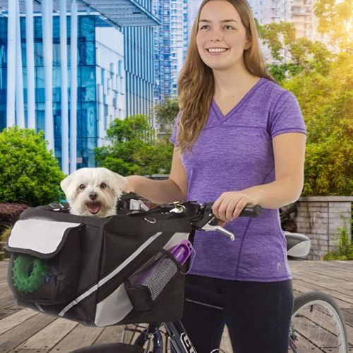 Femme souriante guidant un vélo équipé d'un panier vélo chien noir avec un bichon maltais.