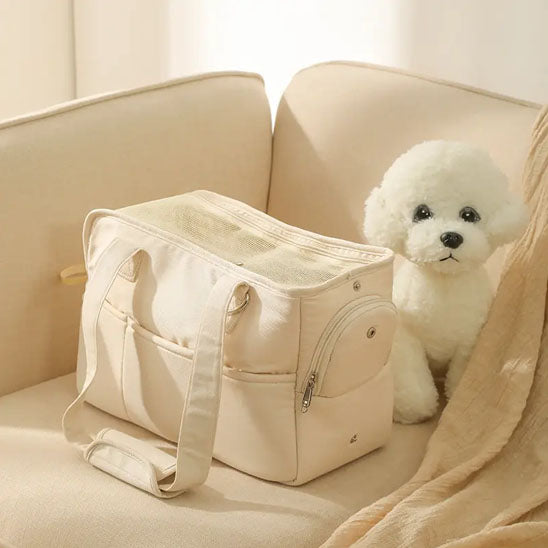 Sac de transport pour chien-ChicStroll™ : Ce caniche nain est confortablement assis dans un sac de transport de couleur blanche posé sur le canapé