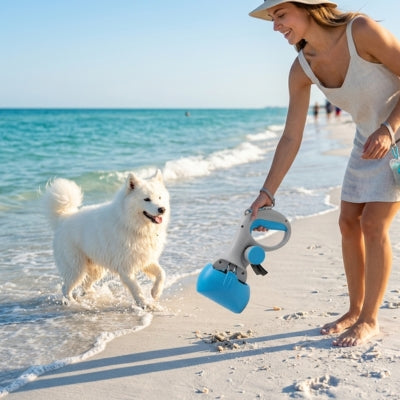 Femme sur la plage utilisant un ramasse crotte pour chien bleu près d'un Samoyède blanc.