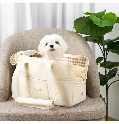 Sac de transport pour chien-ChicStroll™ : Regerde ce mignon caniche nain en sécurité et confortable dans son sac de transport de couleur blanche posé sur le fauteuil