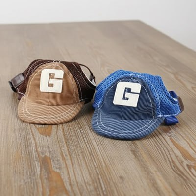 Deux modèles de casquette chien avec logo G, l'une marron et l'autre bleue, posées sur du bois.