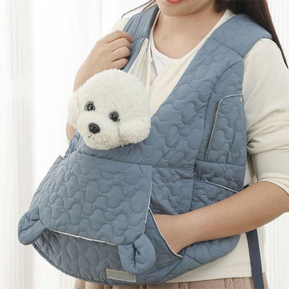 Petit Bichon Frise blanc depassant d'un sac de transport bleu matelasse porte a l'epaule.