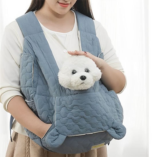 Main caressant un Bichon blanc dans son sac de transport bleu, modele avec petites oreilles.