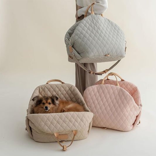 Trois modèles de sac de transport pour chien en beige, rose et gris portés à l'épaule.