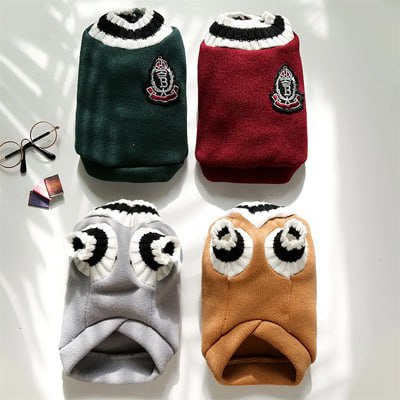 Quatre modèles de pull pour chien avec écusson brodé et col rayé, présentés à plat.