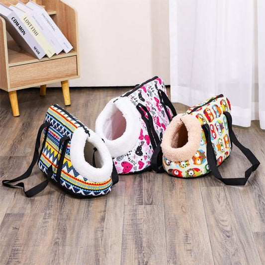 Trois modèles de sac de transport chien (aztèque, cœurs, chouettes) posés sur un parquet.