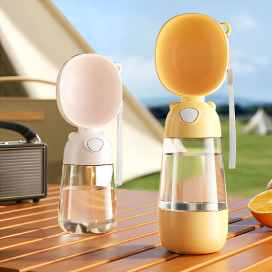 Deux gourdes pour chien, jaune et rose pastel, posées sur une table de jardin en bois.