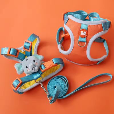 Ensemble harnais chien orange et bleu avec laisse et peluche éléphant sur fond orange.