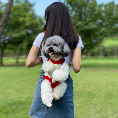 Vue arrière d'une femme portant un caniche gris dans un sac de transport pour chien rouge.