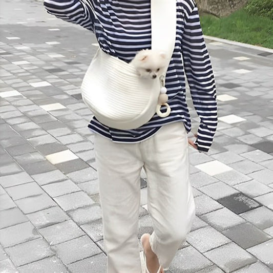Femme marchant avec un petit chien blanc dans un chien sac de transport bandoulière crème.