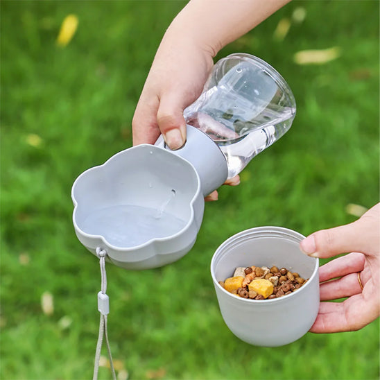 Main tenant une gourde chien grise versant de l'eau et un compartiment de croquettes.