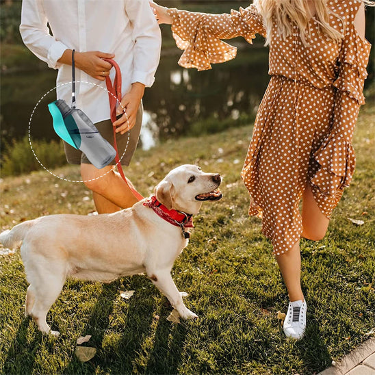 Labrador beige en laisse et gourde chien turquoise portée par un homme en extérieur.