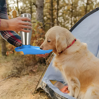 Golden Retriever buvant dans une gourdes pour chiens bleue devant une tente de camping en forêt.