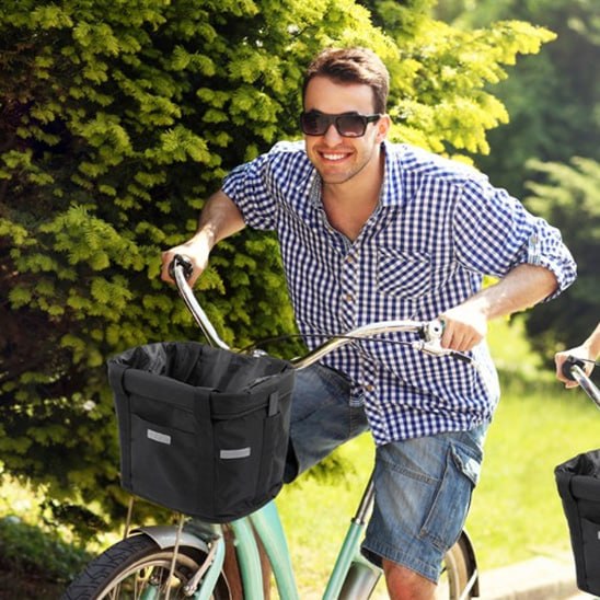 Homme cycliste souriant avec un panier velo chien noir fixé sur son guidon chromé.