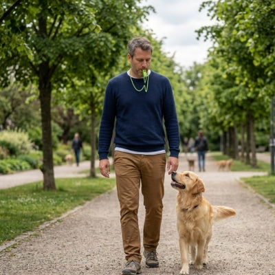 Homme marchant avec un sifflet pour chien ultrason au cou et un Golden Retriever à ses côtés.