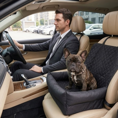 Bouledogue français assis dans une housse protection voiture chien noire sur siège avant.