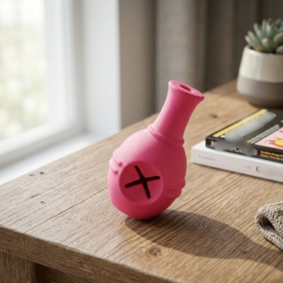 Jouet pour chien kong rose avec ouverture en croix posé sur un meuble en bois clair.