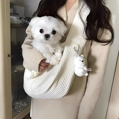 Gros plan d'un Maltais blanc dans un chien sac de transport avec peluche accrochée.