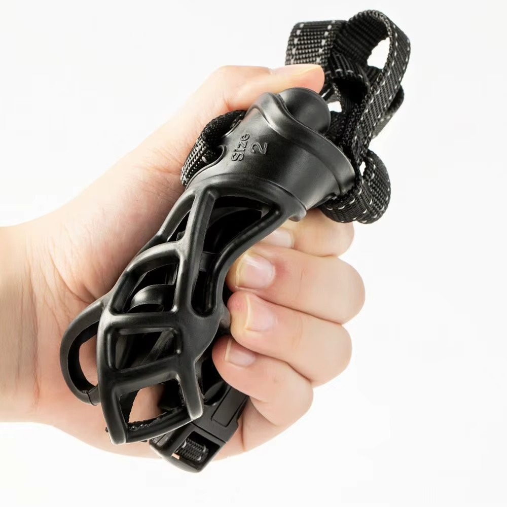 Main serrant une muselière pour chien noire souple de taille 2.