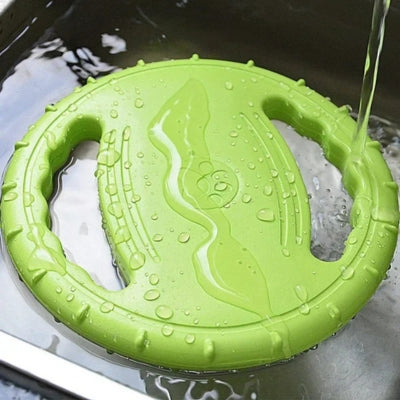Gros plan d'un jouet pour chien vert avec empreinte de patte, flottant et rincé sous l'eau.