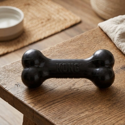 Gros plan d'un os jouet pour chien kong noir avec logo gravé posé sur une table en bois rustique.