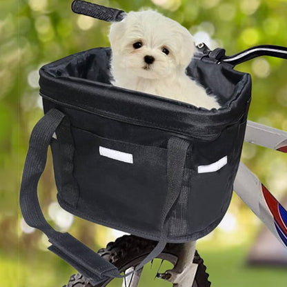 Chiot Bichon maltais blanc installé dans un panier velo chien noir sur un guidon.