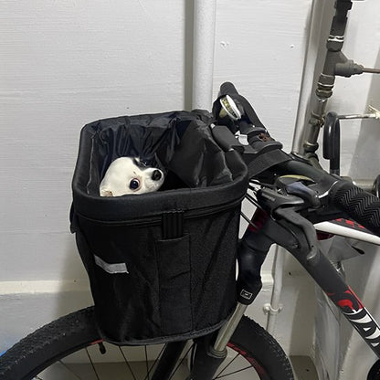 Petit chien Chihuahua blanc et noir dans un panier velo chien noir à l'intérieur.