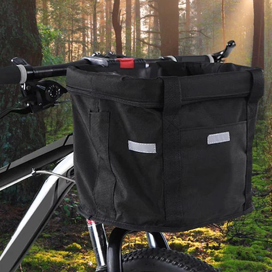 Panier velo chien noir fixé sur un VTT avec un arrière-plan de forêt ensoleillée.