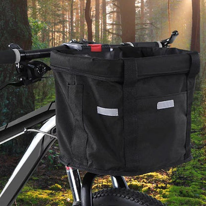 Panier velo chien noir fixé sur un VTT avec un arrière-plan de forêt ensoleillée.