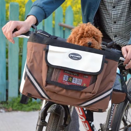 Caniche brun dans un panier vélo chien marron marqué Petcomer sur le guidon.