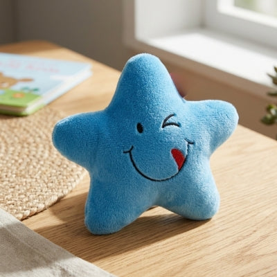 Peluche pour chien en forme d'étoile bleue avec un sourire et un clin d'œil posée sur une table.