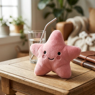 Peluche pour chien rose en forme d'étoile avec des joues roses sur une table en bois.