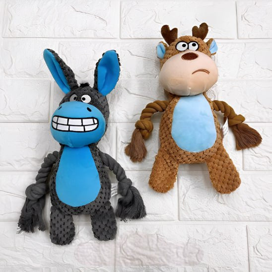 Peluche pour chiens en forme d'âne gris et de cerf marron sur un mur en briques blanches.
