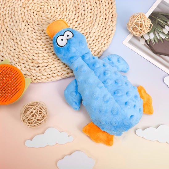 Gros plan d'une peluche pour chiens en forme de canard bleu posée sur un tapis tressé.