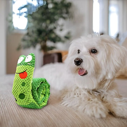 Petit Bichon maltais blanc observant une peluche pour chiens en forme d'escargot vert.