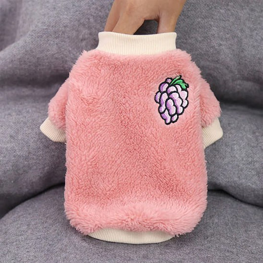 Pull pour chien rose en laine polaire avec un motif raisin, vue sur support.