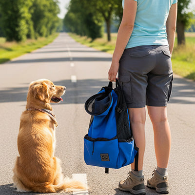 Femme tenant un sac a dos chien bleu vide à côté d'un Golden Retriever sur une route.