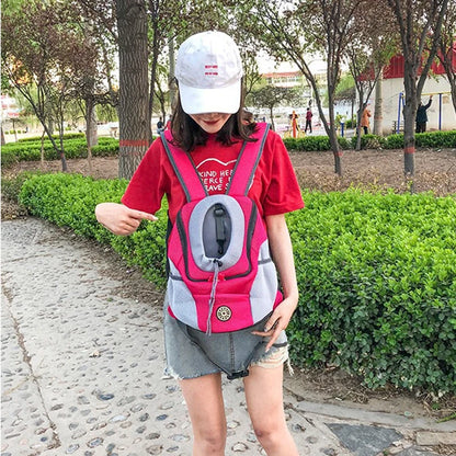 Femme portant un petit sac à dos chien fuchsia sur le ventre dans un parc.
