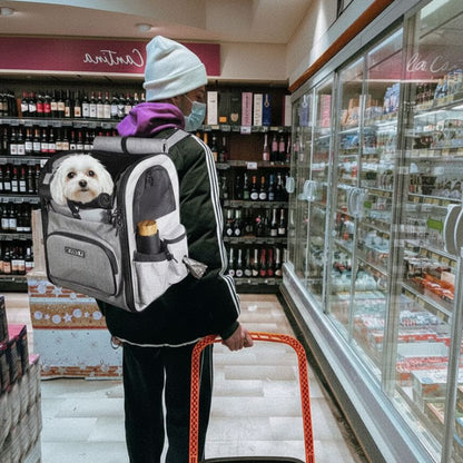 Homme en magasin portant un sac a dos pour chien gris avec un petit chien blanc à bord.