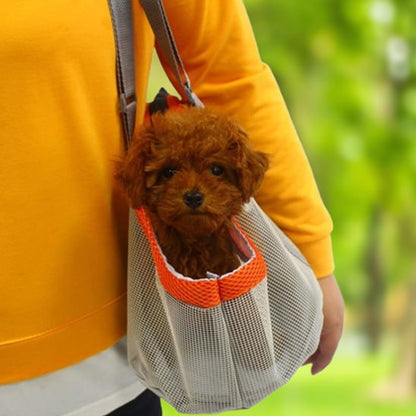Petit caniche brun dans un sac de transport chien gris et orange porté en bandoulière.