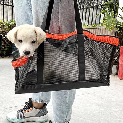 Chiot blanc passant la tête hors d'un sac de transport chien noir et orange porté à l'épaule.