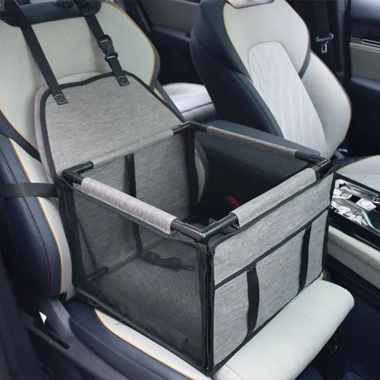 Panier de transport vide type siege auto chien gris installé sur un siège de voiture blanc.