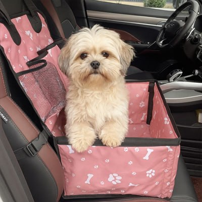 Chien Shih Tzu beige installé confortablement dans un siege auto chien rose en voiture.
