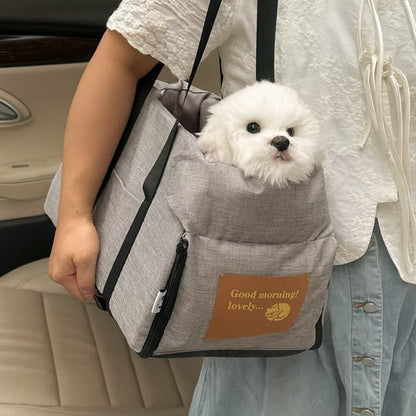 Bichon blanc porté à l'épaule dans son siege auto chiens gris, écusson "Good morning! lovely...".