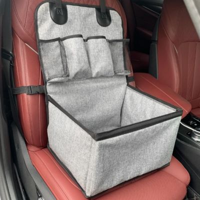 Vue vide d'un siege auto pour chien gris robuste installé sur un siège de voiture rouge.