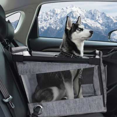 Chien Husky sibérien dans un siege auto pour chien gris devant des montagnes enneigées.