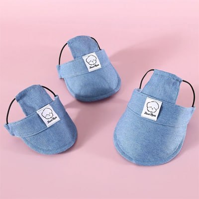 Trois modèles de casquette chien en denim bleu avec écusson blanc posés sur fond rose.