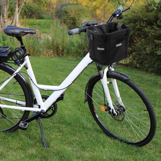 Vélo de ville blanc avec béquille et panier velo chien noir monté sur le guidon.