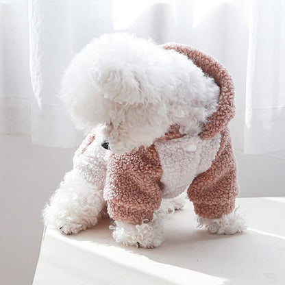 Bichon de profil portant un vêtement pour chien à capuche en sherpa rose et blanc.