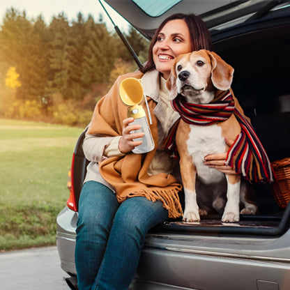 Femme tenant une gourdes pour chien jaune à côté d'un chien Beagle dans le coffre d'une voiture.